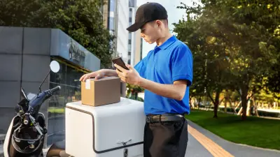 Male delivery driver closing a scooter mounted box.